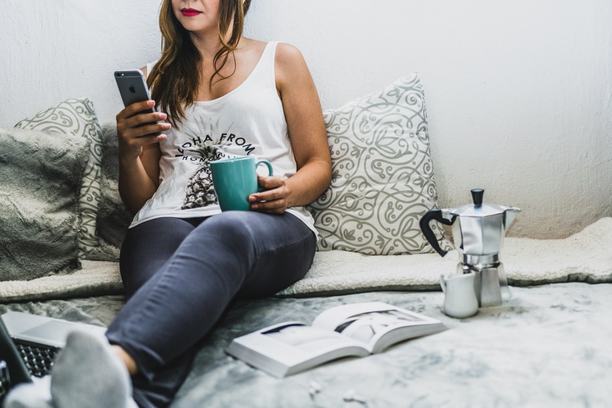 woman sitting on bed with phone writing shareable blog content